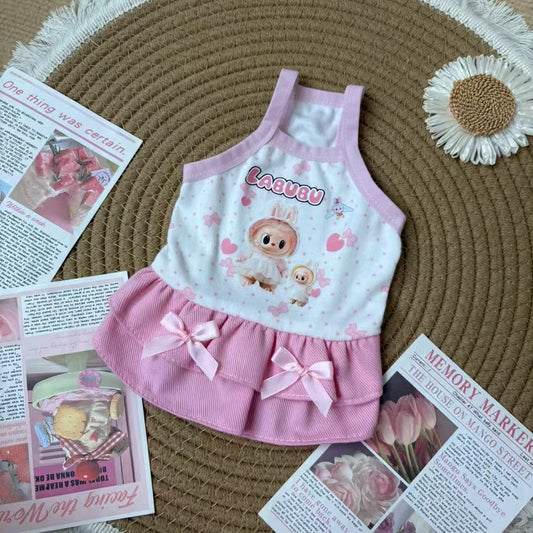 Pink and white dress with cartoon character for small dog on a textured surface with magazines.